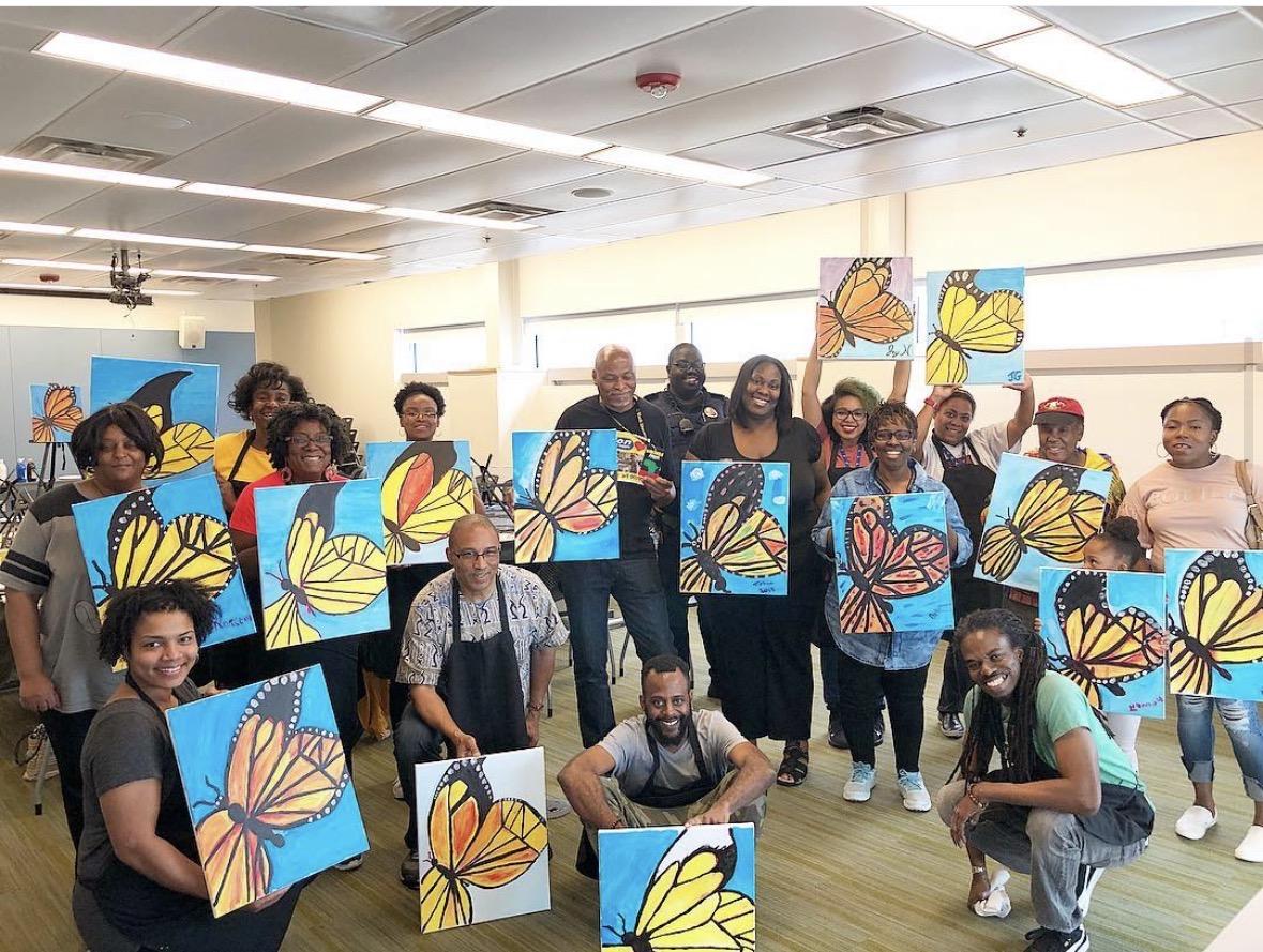 Group of participants proudly holding their butterfly paintings